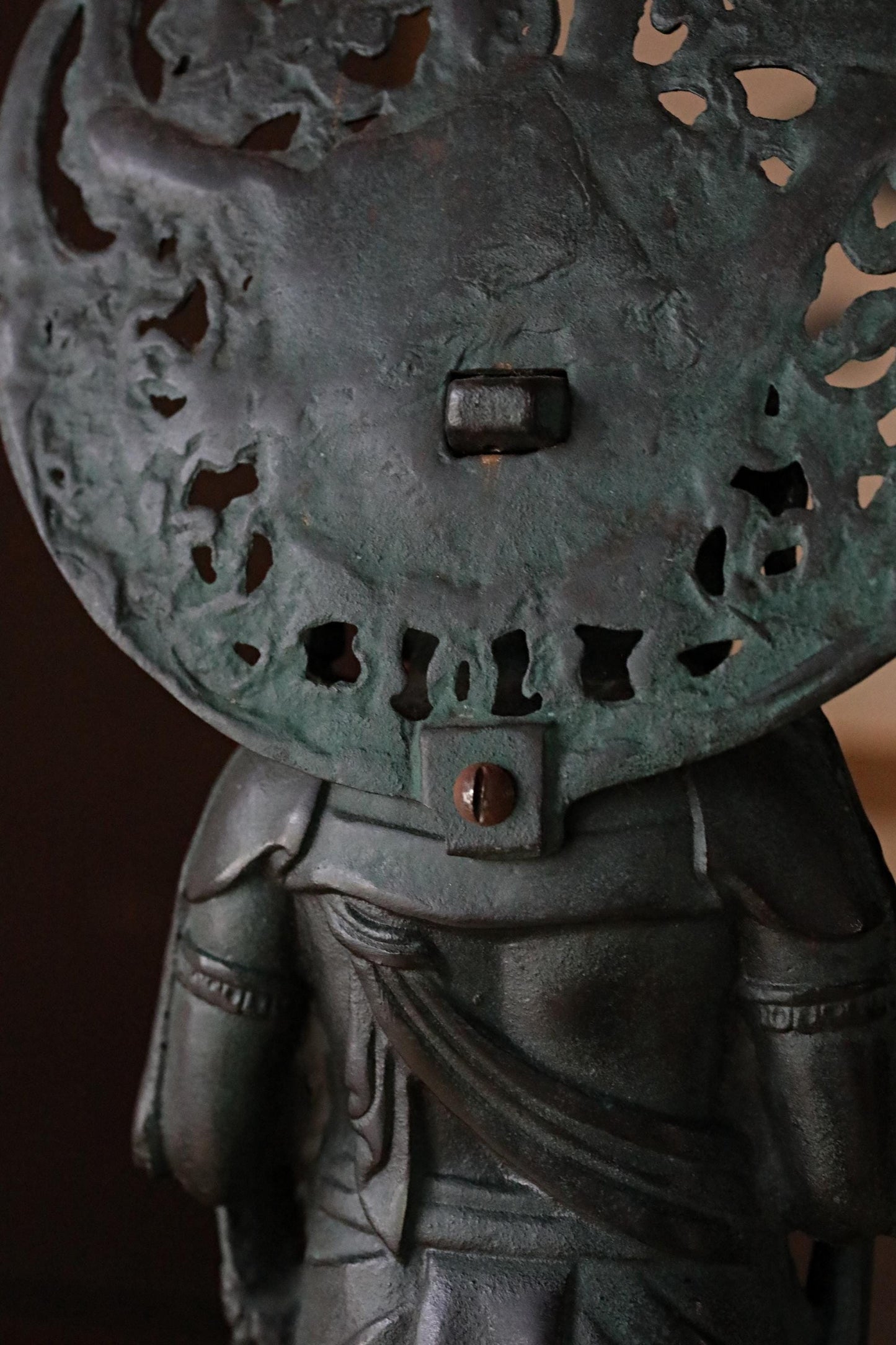 a close-up view of a dark green metal sculpture with intricate designs and patterns.