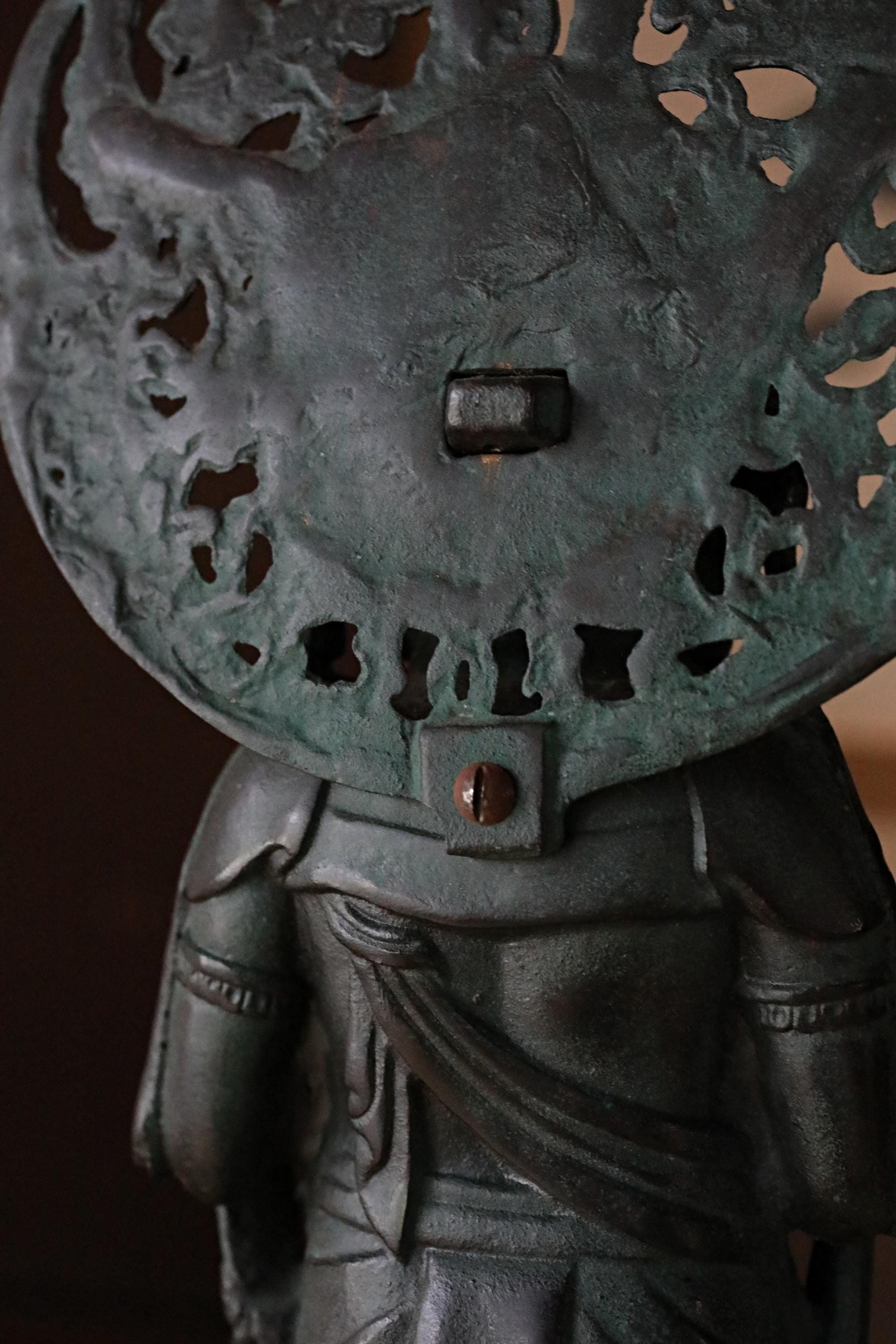 a close-up view of a dark green metal sculpture with intricate designs and patterns.