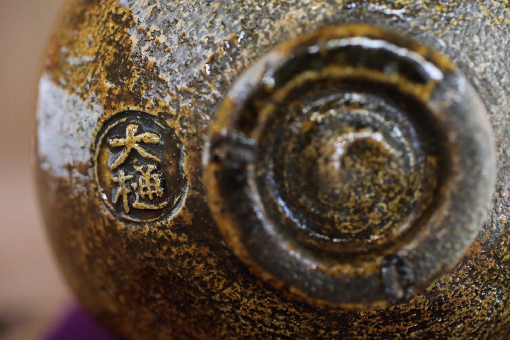 A close-up image of a ceramic object with a distinctive design, featuring a circular motif and a symbol or text in a non-Latin script.