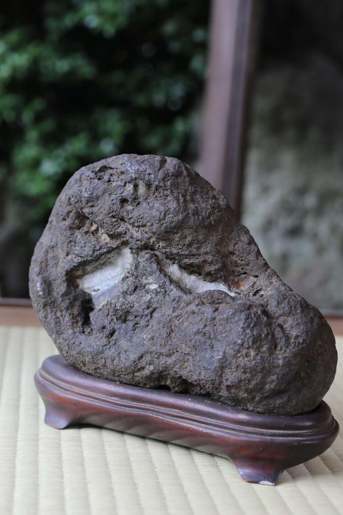 a large, dark rock with a hole in it, sitting on a wooden stand.