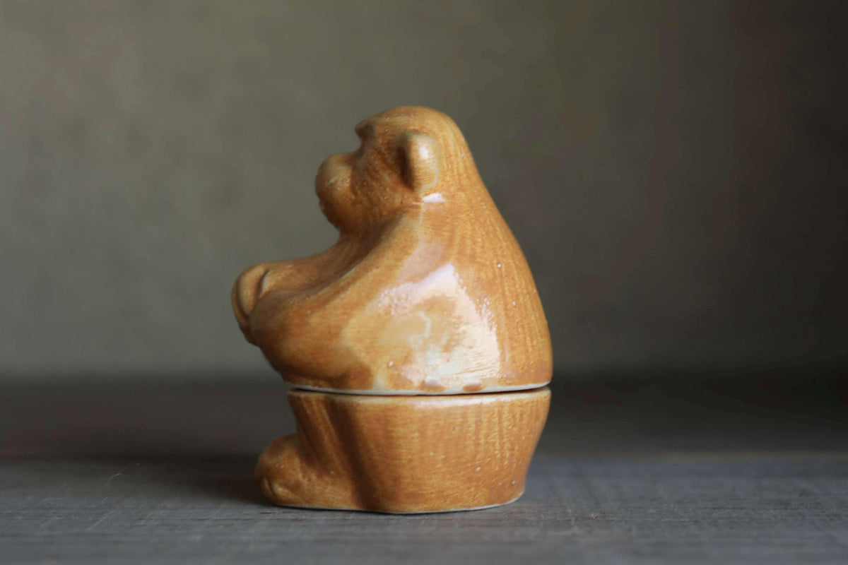 A ceramic monkey figurine sitting on a wooden base.