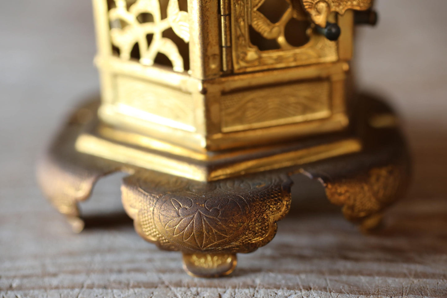 A close-up view of a golden, ornate metal object with intricate designs, resting on a wooden surface.
