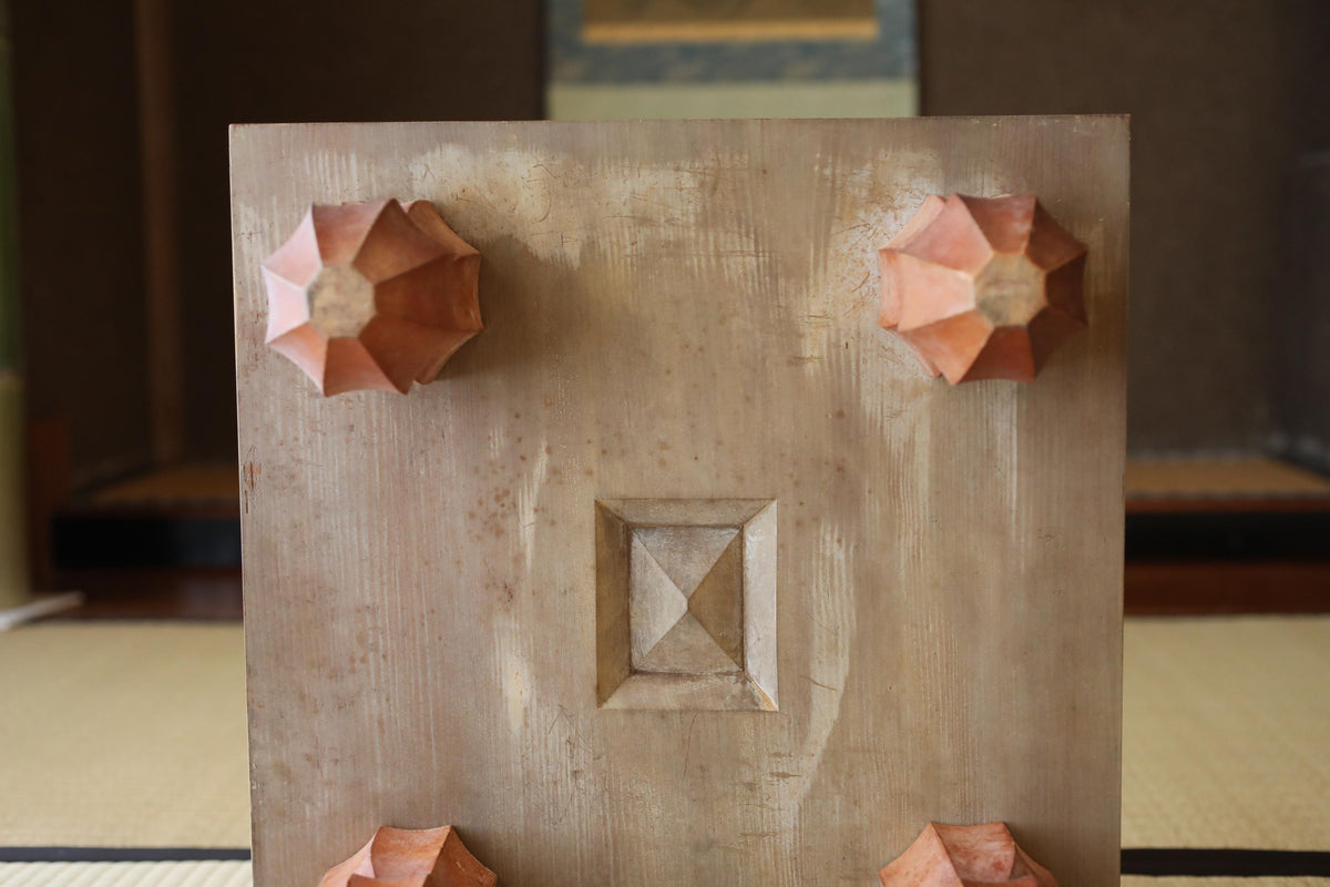 a wooden panel with a carved design, featuring two triangular shapes on either side of a central square design.