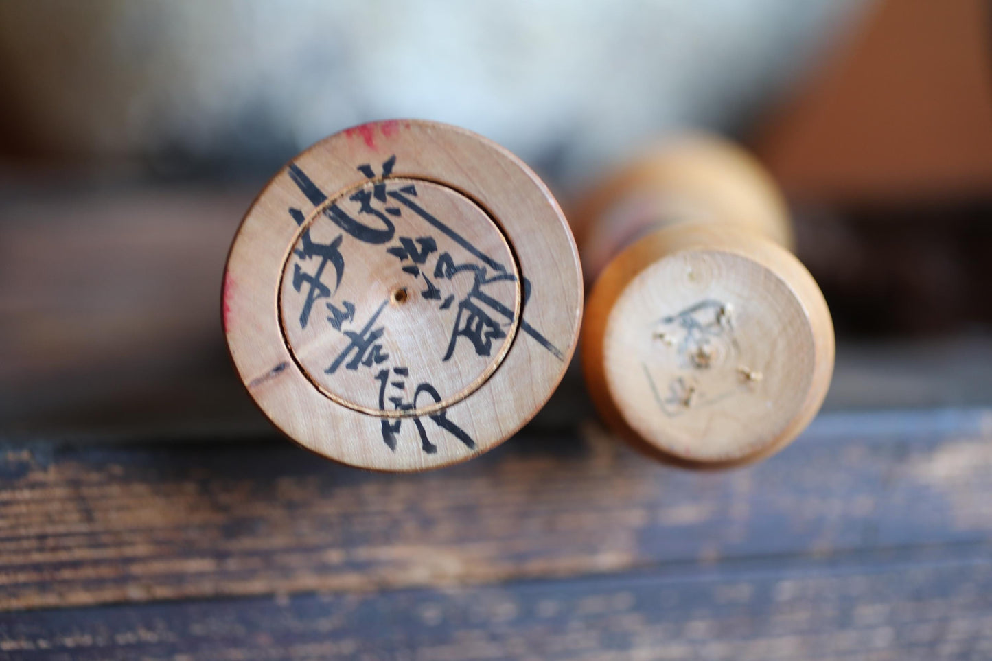 two wooden objects with Asian characters on them, placed on a wooden surface.