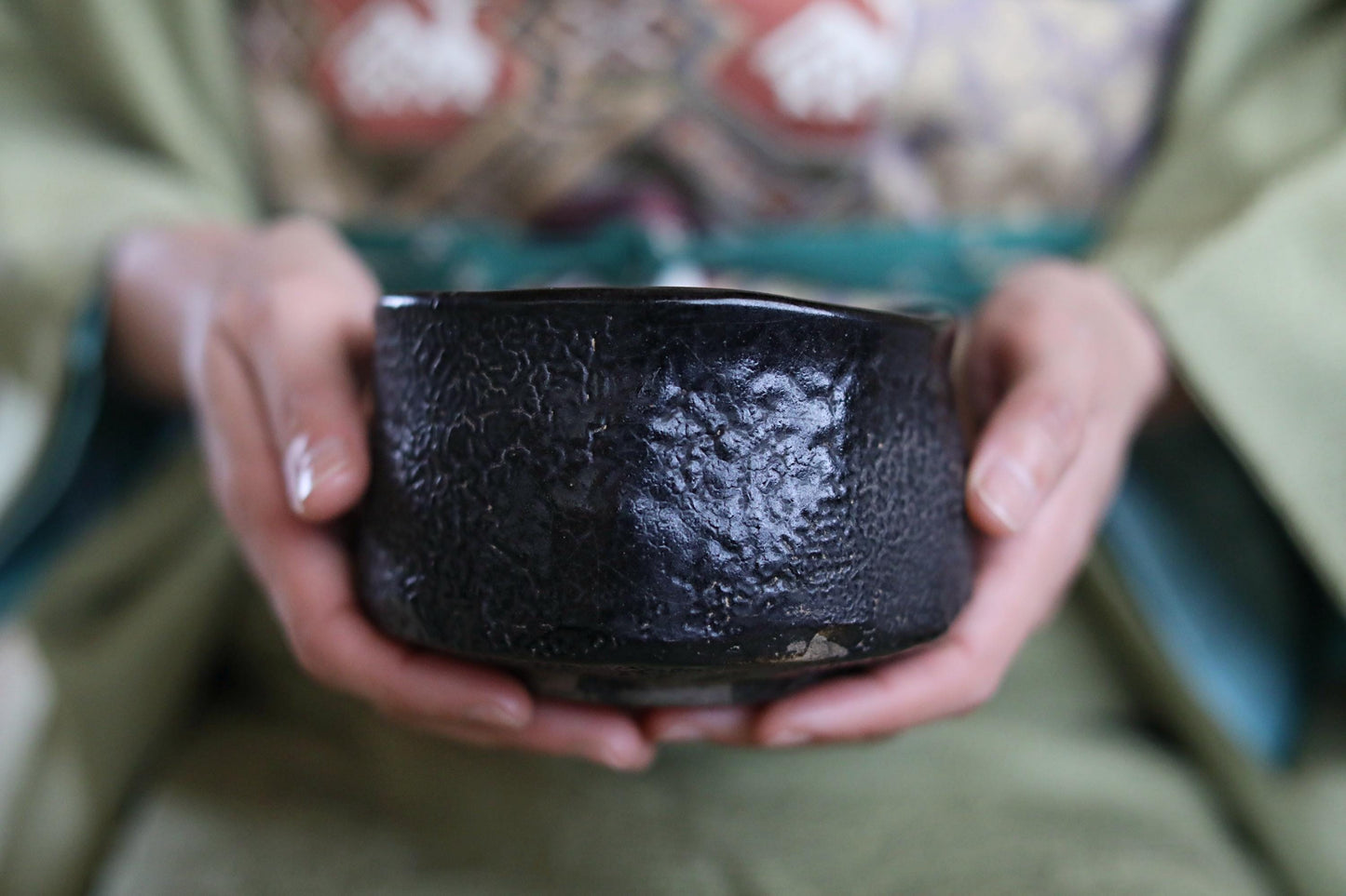 A person's hands holding a black, textured bowl.