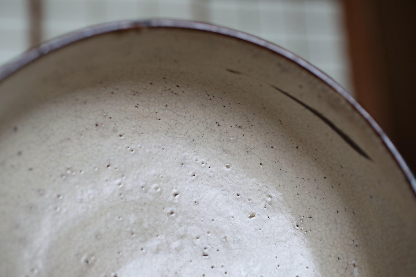 A close-up view of a white ceramic bowl with a speckled texture, featuring a dark rim.