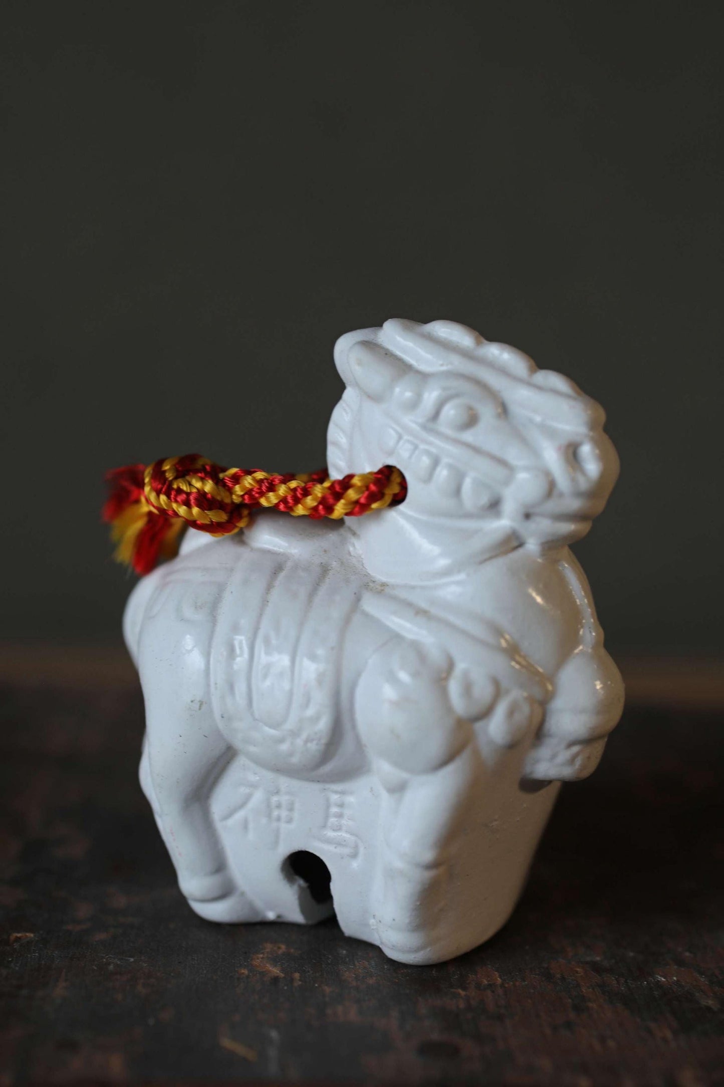 A white ceramic figurine of a lion, possibly a Chinese or Japanese style, is displayed on a wooden surface.