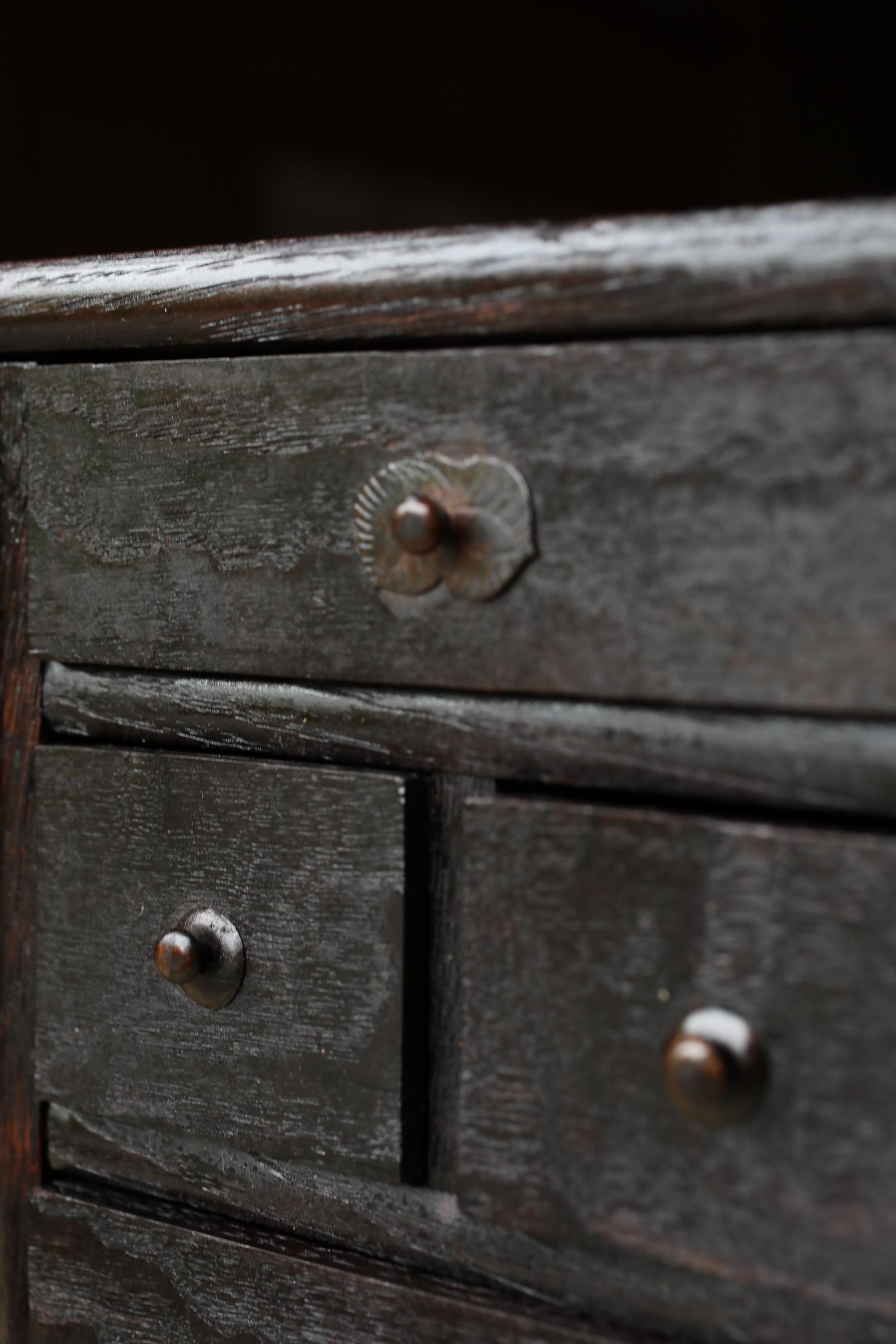a close-up view of a wooden cabinet with three drawers, featuring a metal handle on the left side.