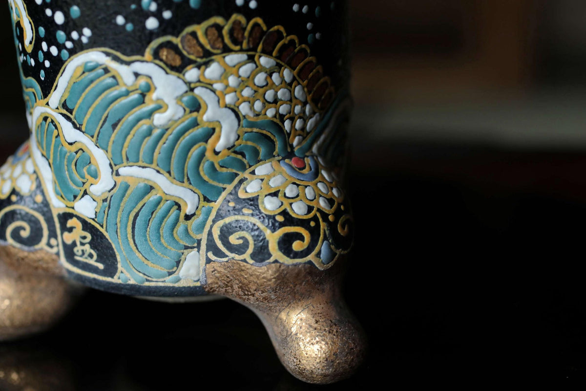 A close-up view of a decorative ceramic vase with intricate patterns and designs in gold, blue, and white colors.