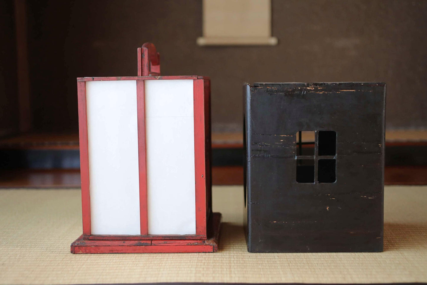 a red lantern and a black box, both sitting on a mat.