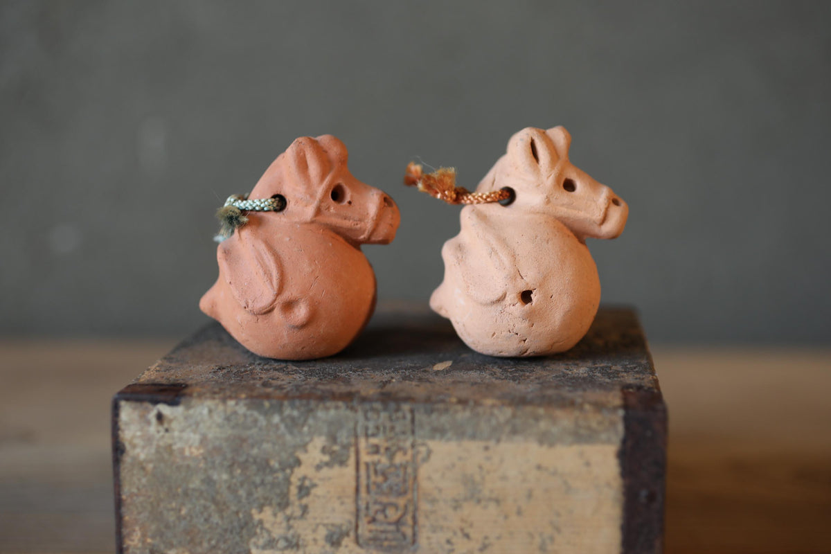 Two clay figurines of a dragon and a horse are sitting on a wooden surface.