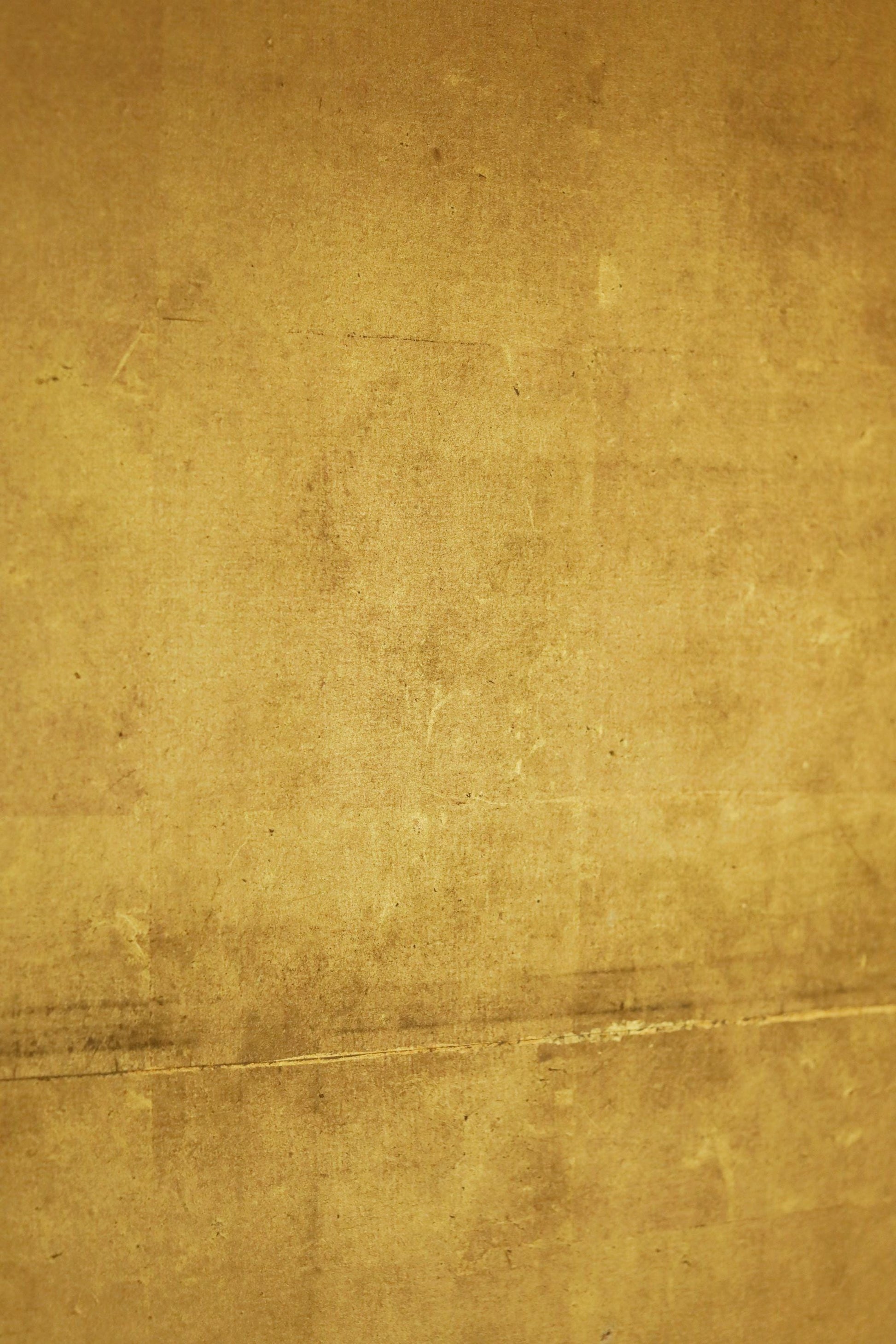 The image is a close-up of a textured surface, possibly a wall or a piece of paper, with a warm, golden-brown color.