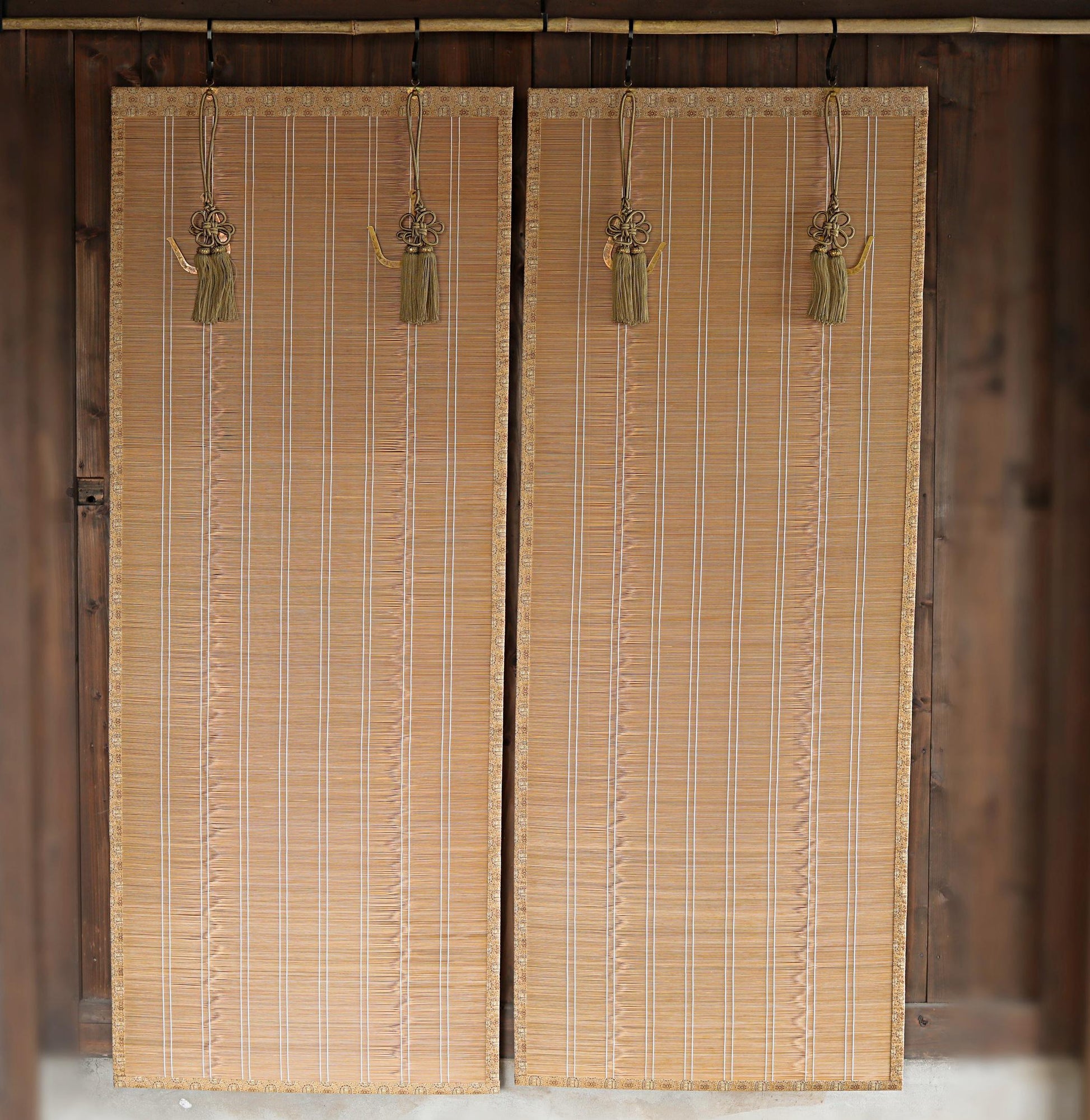 a pair of wooden blinds hanging on a wall, with tassels hanging from them.