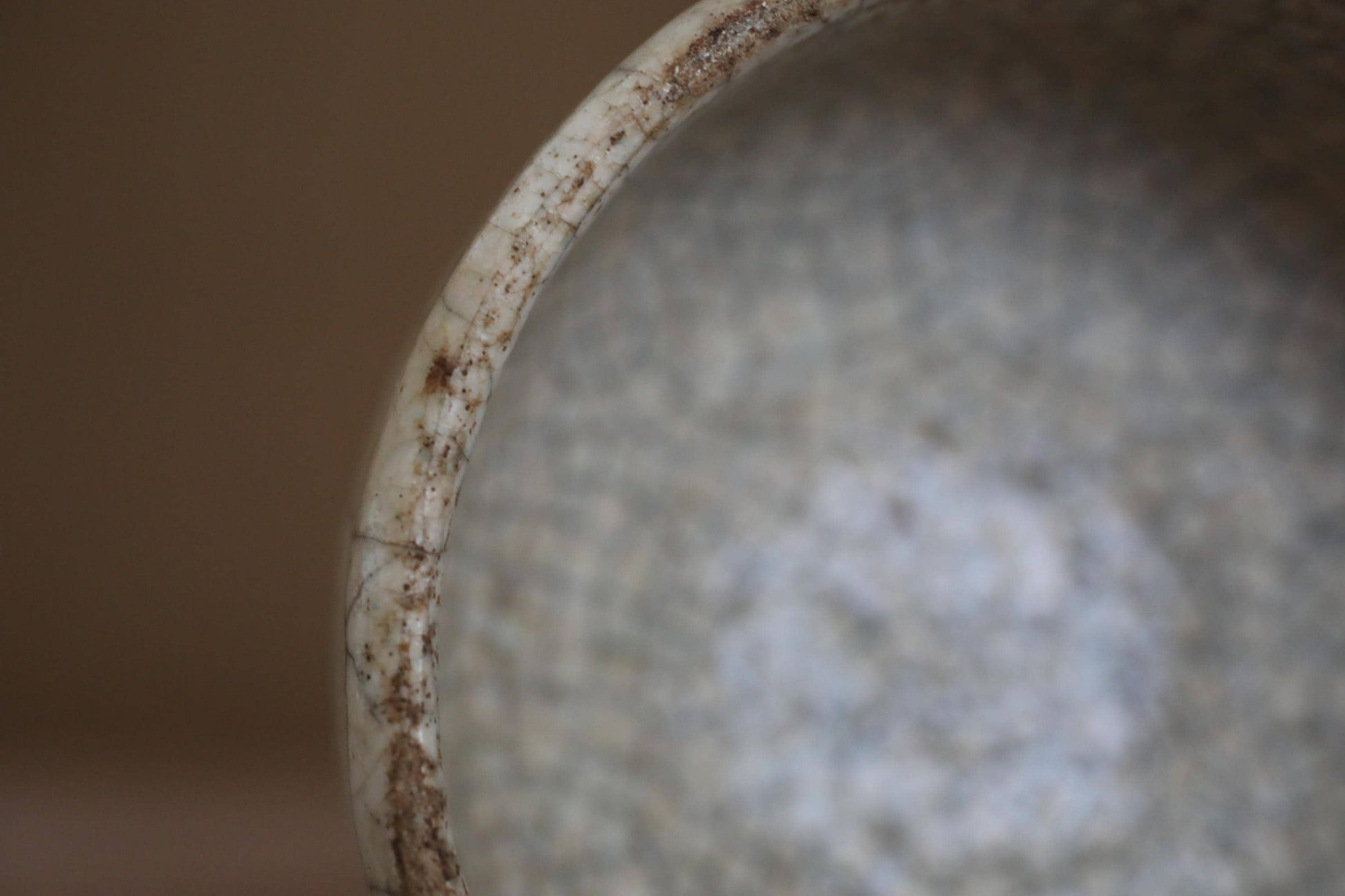 A close-up view of a dirty, textured surface with a white, curved edge.