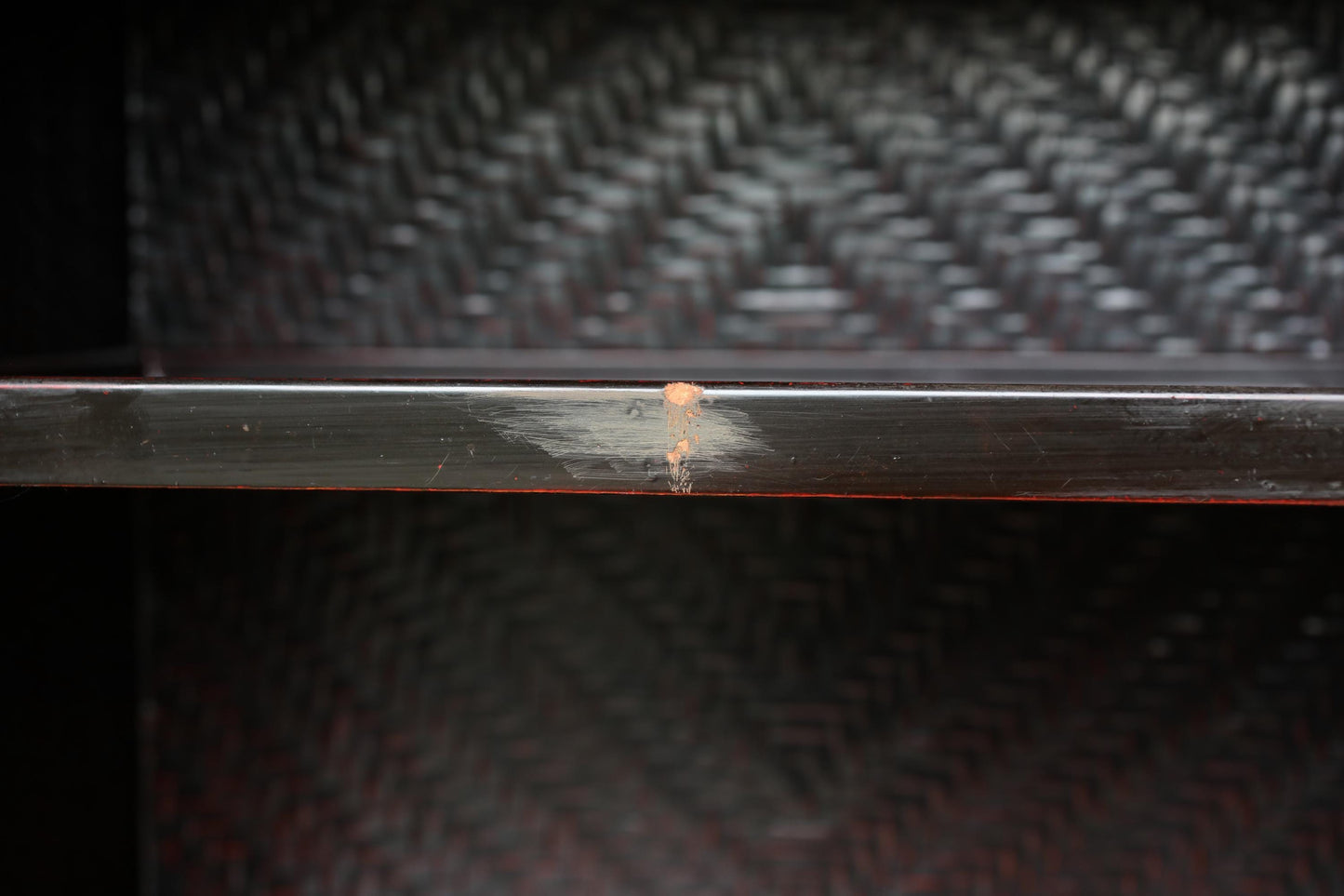 a close-up view of a dark wooden shelf with a visible crack on its surface.