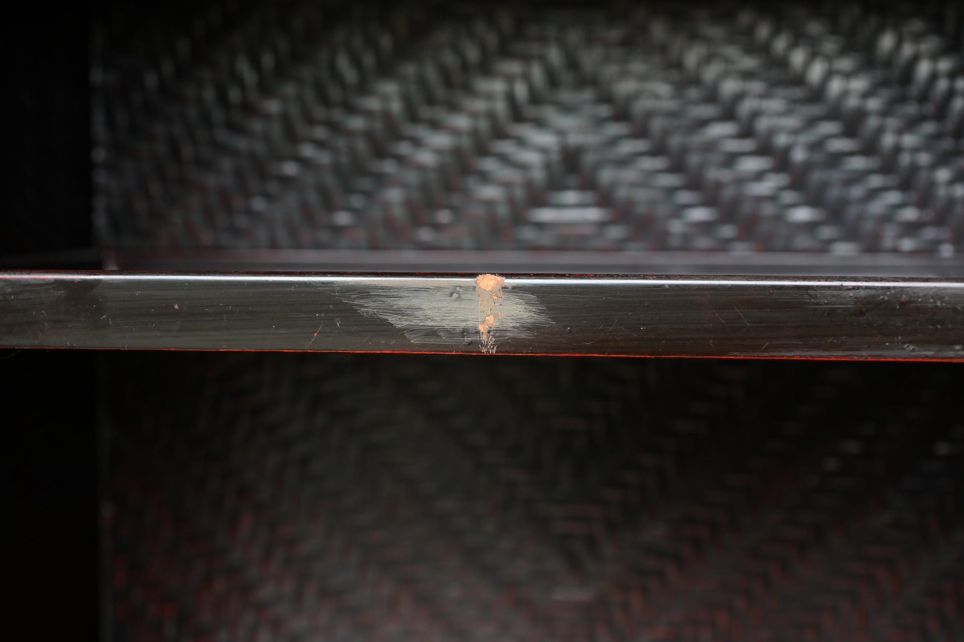 a close-up view of a dark wooden shelf with a visible crack on its surface.