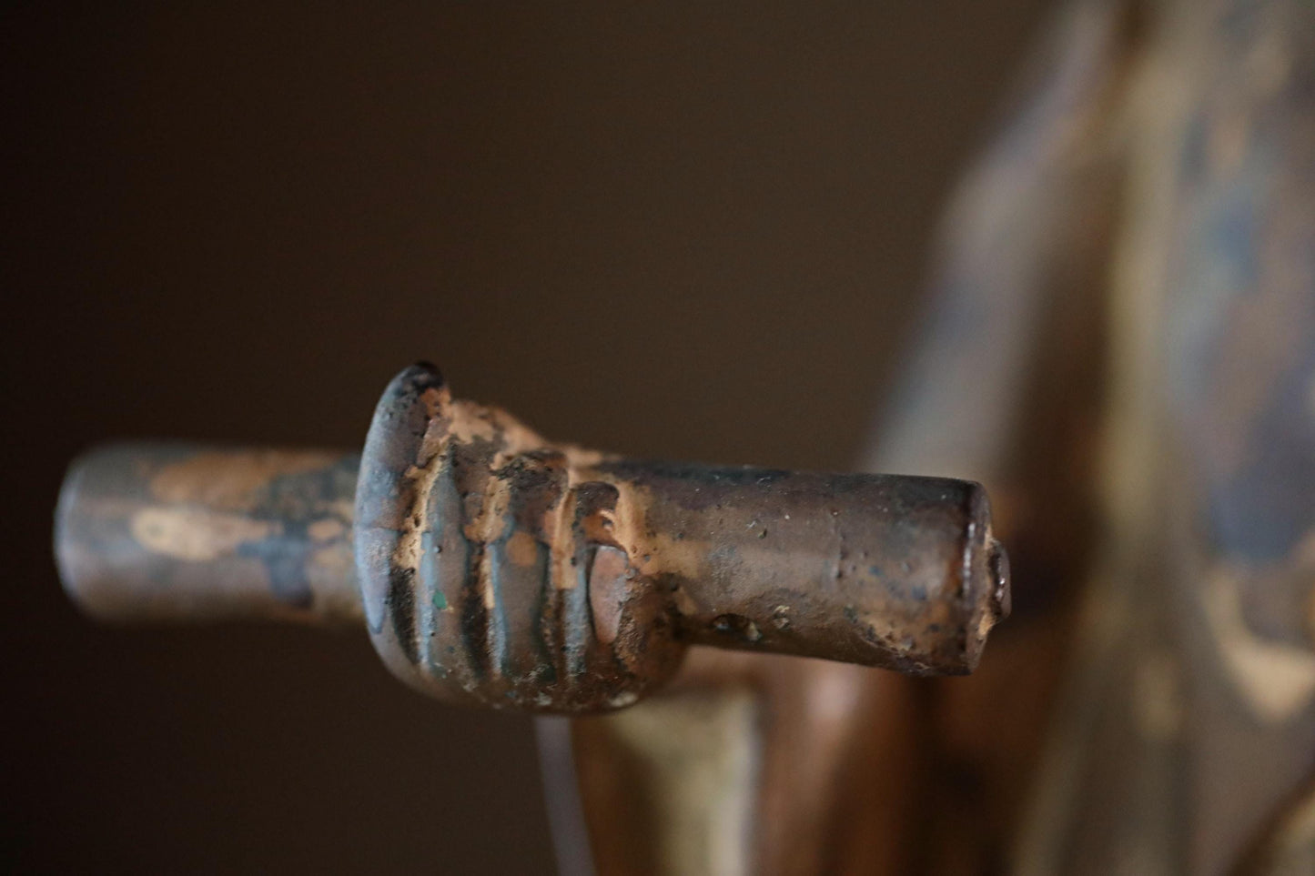 A close-up view of a rusted metal object, possibly a handle or knob, with a weathered and aged appearance.