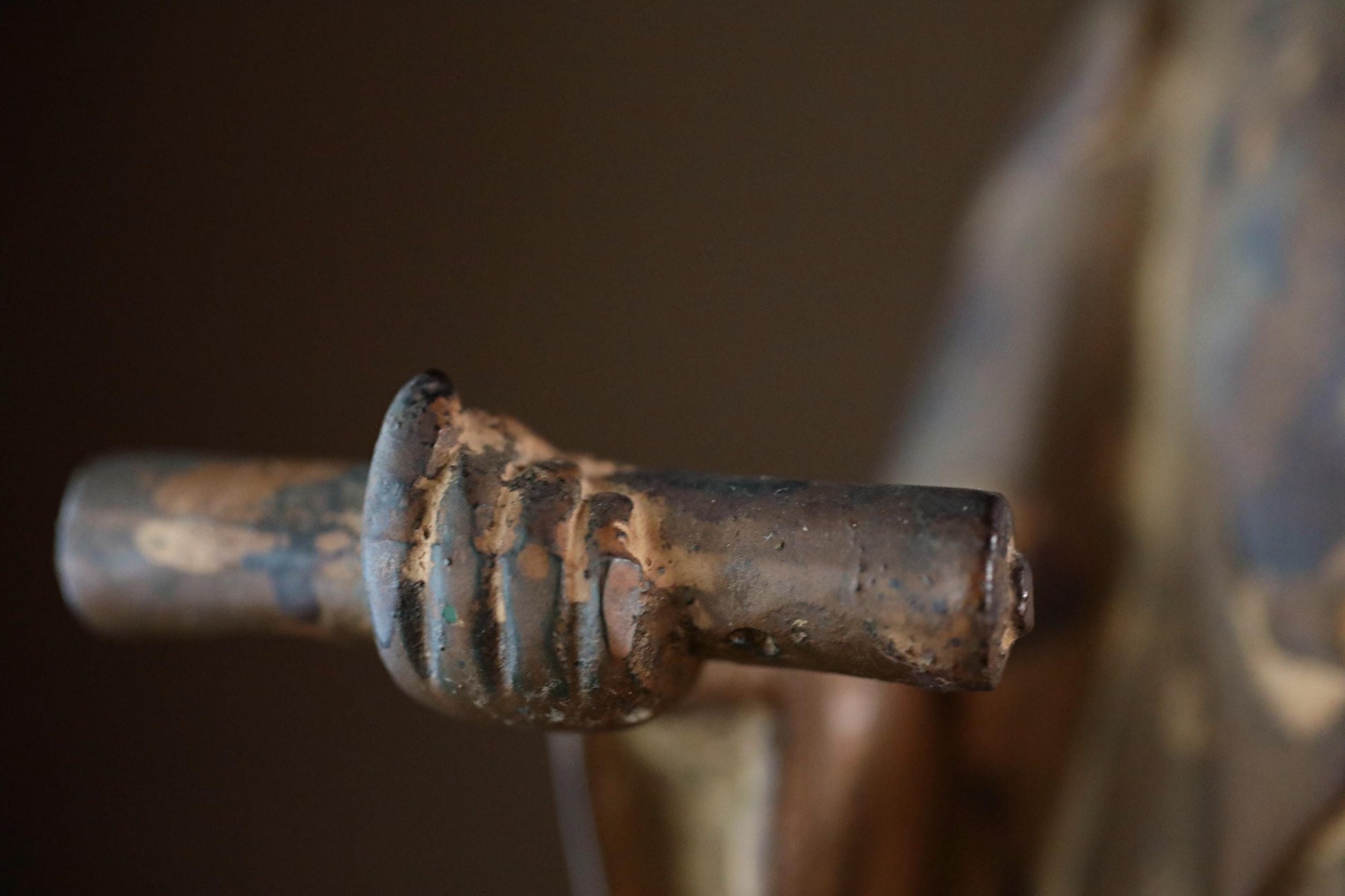 A close-up view of a rusted metal object, possibly a handle or knob, with a weathered and aged appearance.
