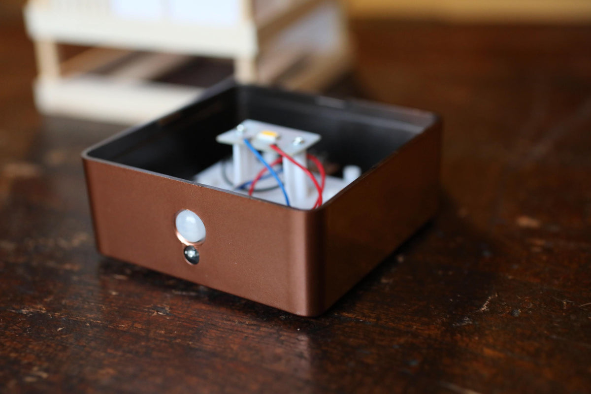 a close-up view of a brown electronic device with a white and blue component, placed on a wooden surface.