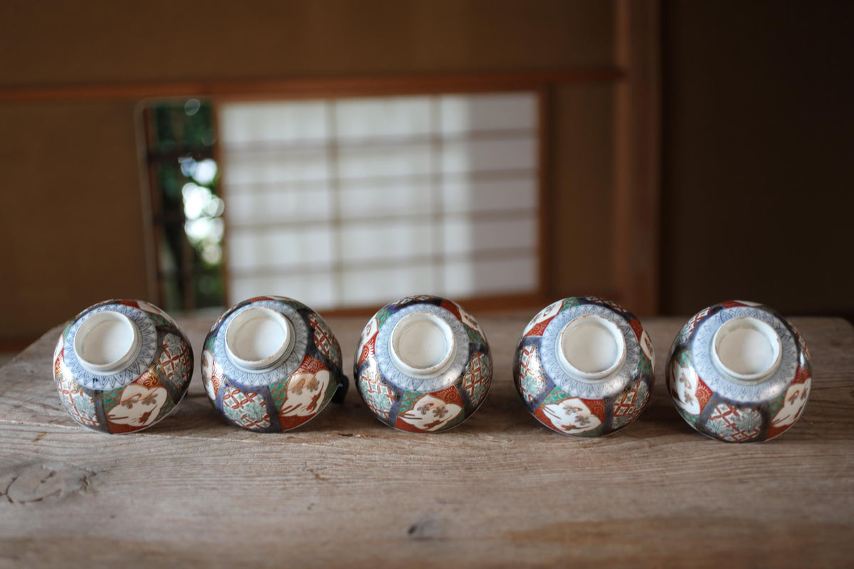 A row of five colorful ceramic vases with intricate designs, arranged on a wooden surface.
