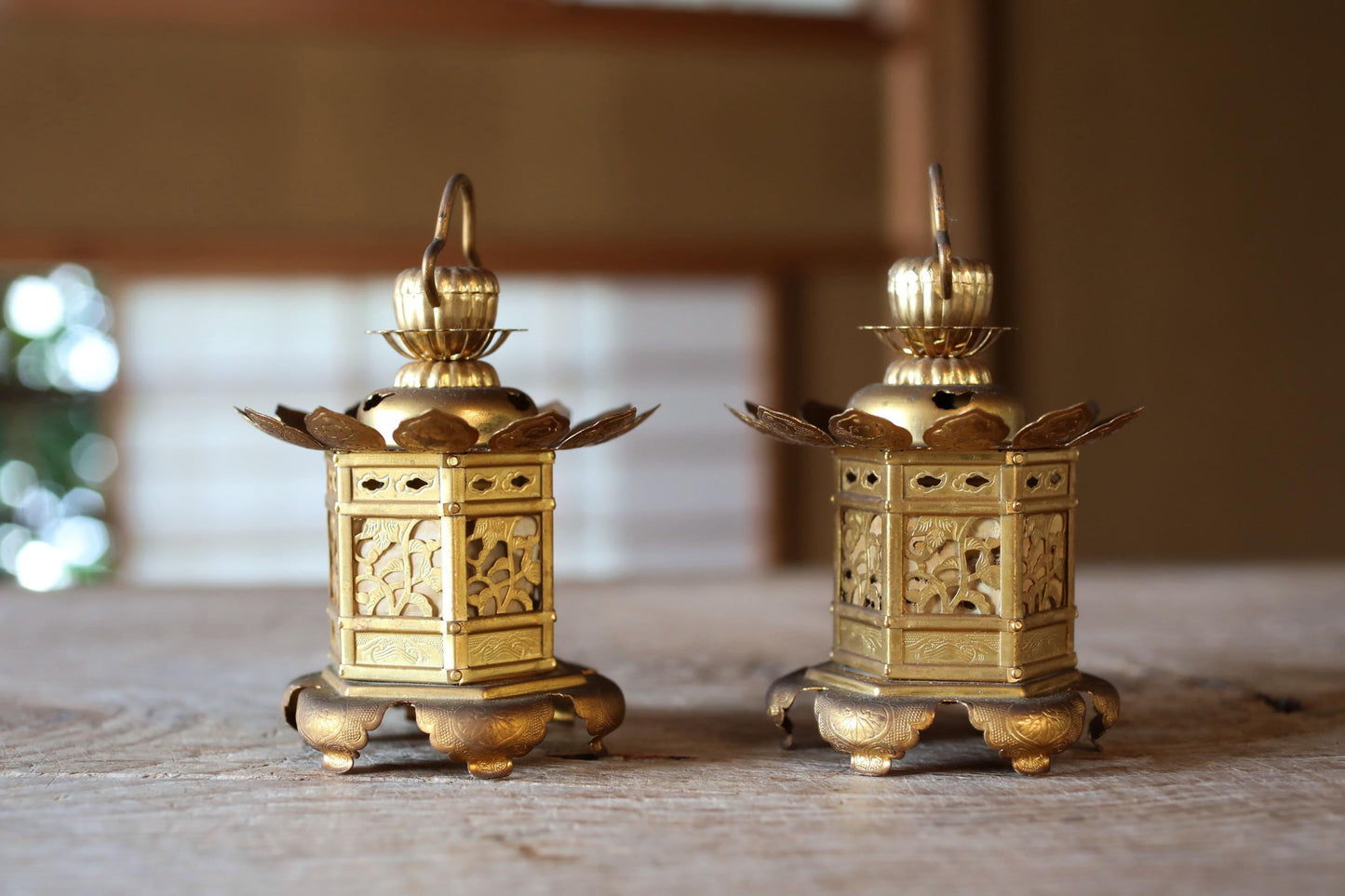 Two ornate golden lanterns with intricate designs are displayed on a wooden surface.
