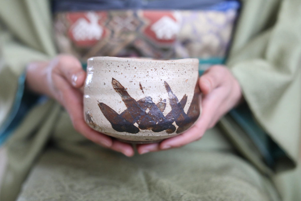 A person's hands holding a ceramic bowl with a decorative design on it.