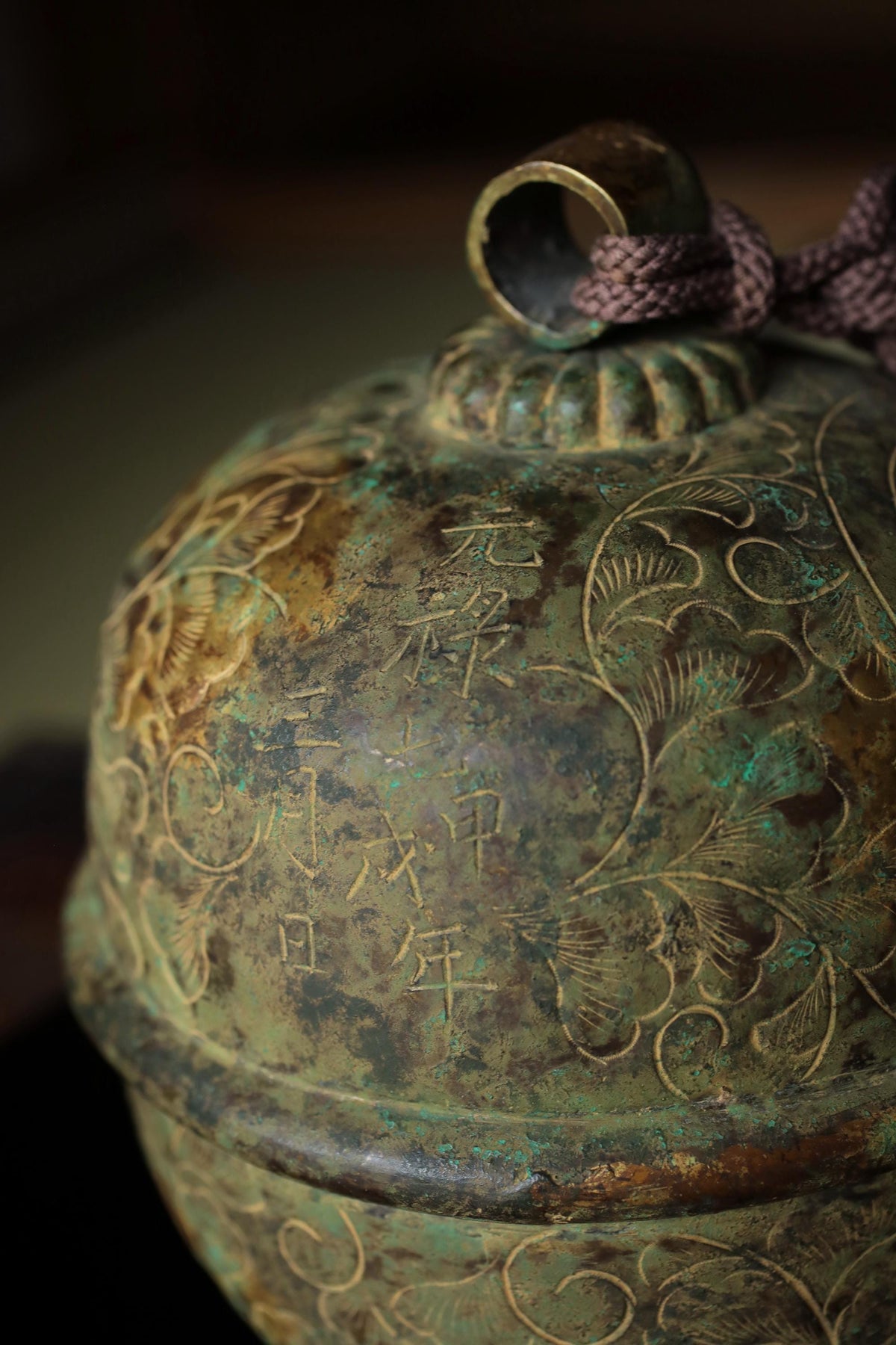 An ornate, antique-looking bell with intricate designs and patterns, including Chinese characters.