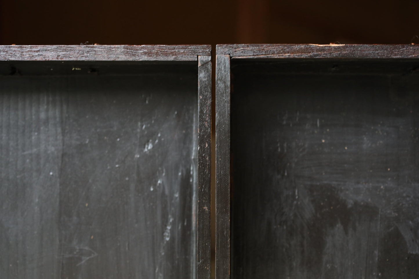 a close-up view of a dark wooden surface with a rough, textured appearance.