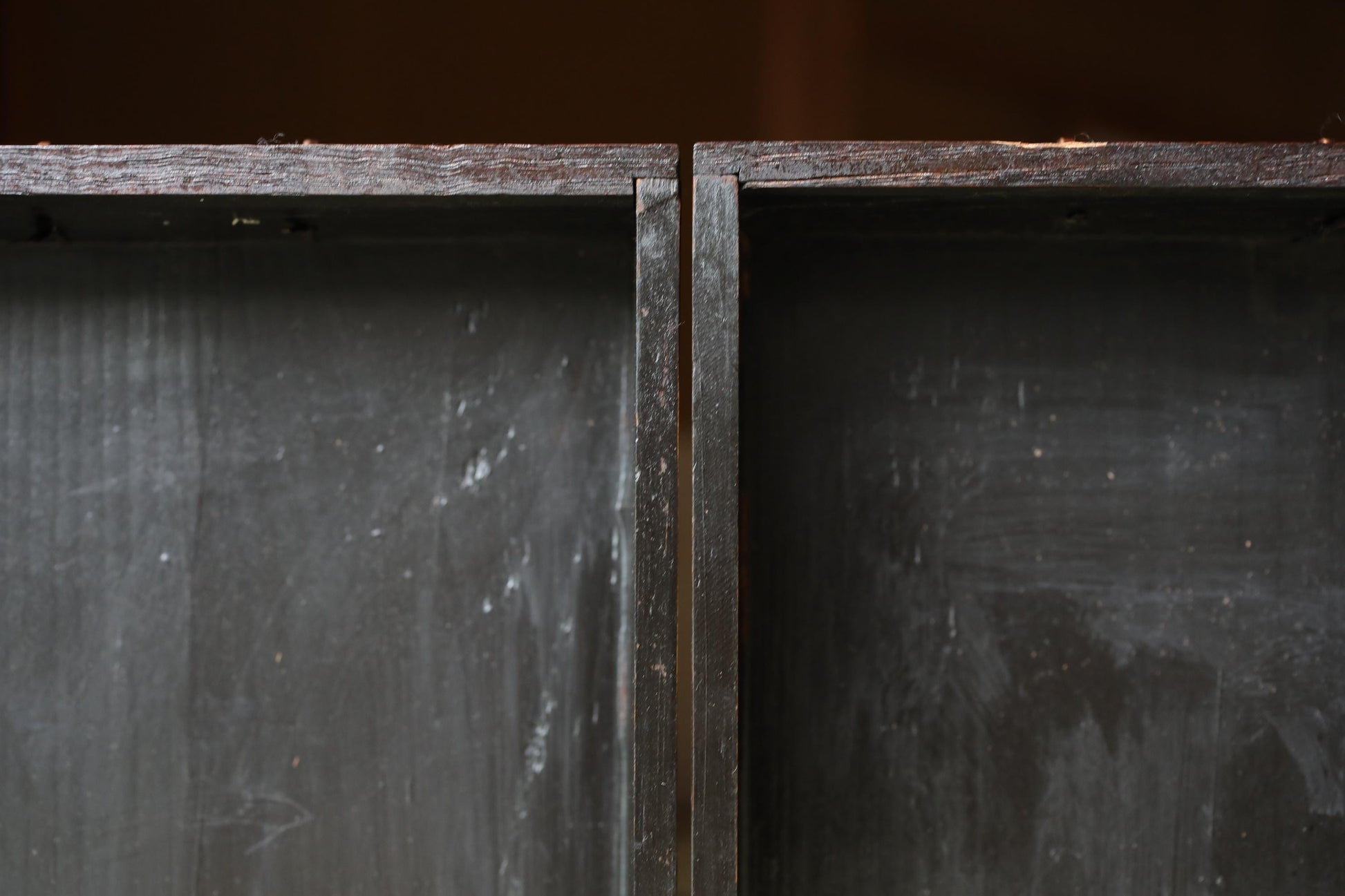 a close-up view of a dark wooden surface with a rough, textured appearance.