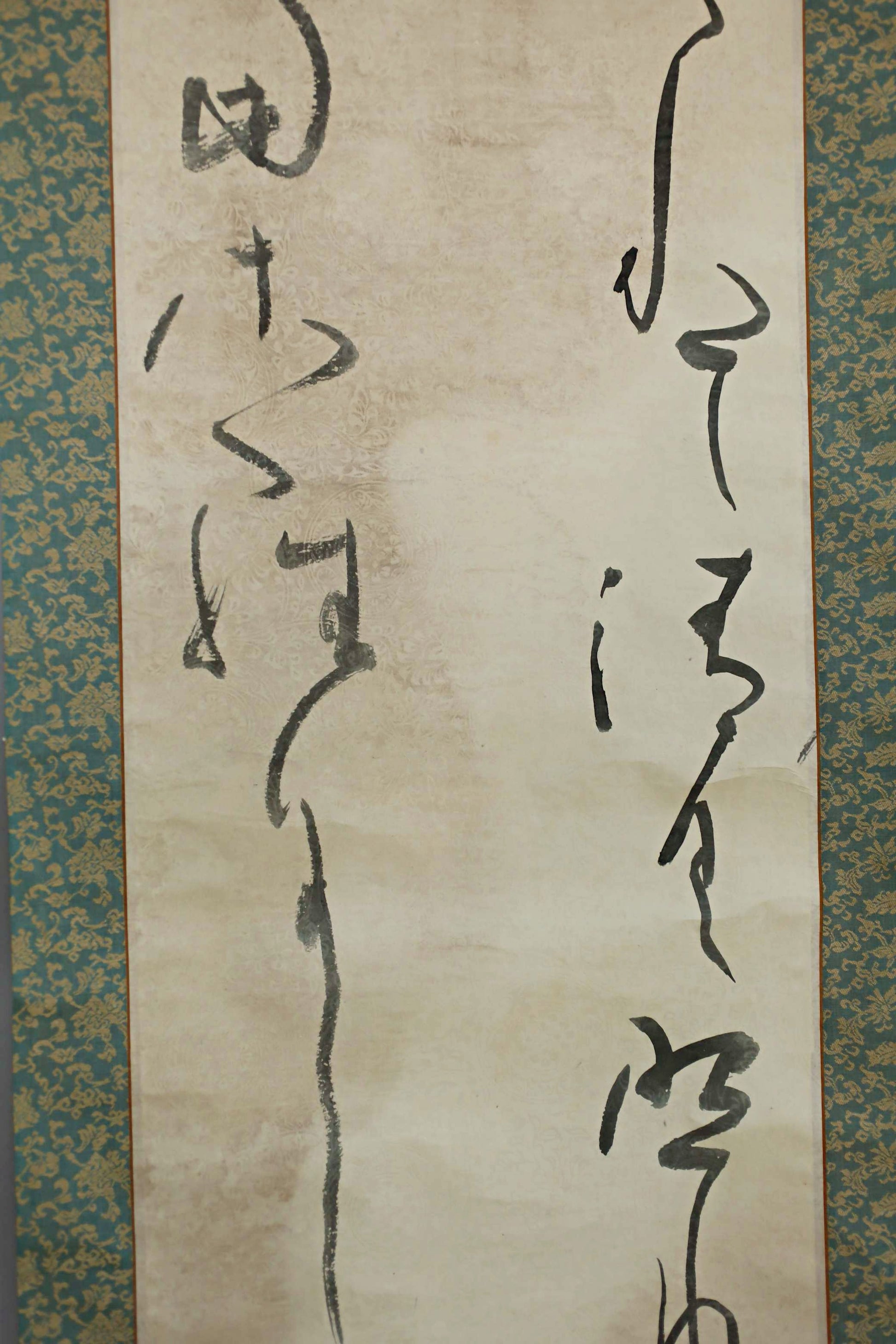 a close-up view of a piece of Chinese calligraphy on a beige background. The calligraphy consists of various characters and strokes, some of which are in black ink. The image does not contain any text beyond the calligraphy itself.