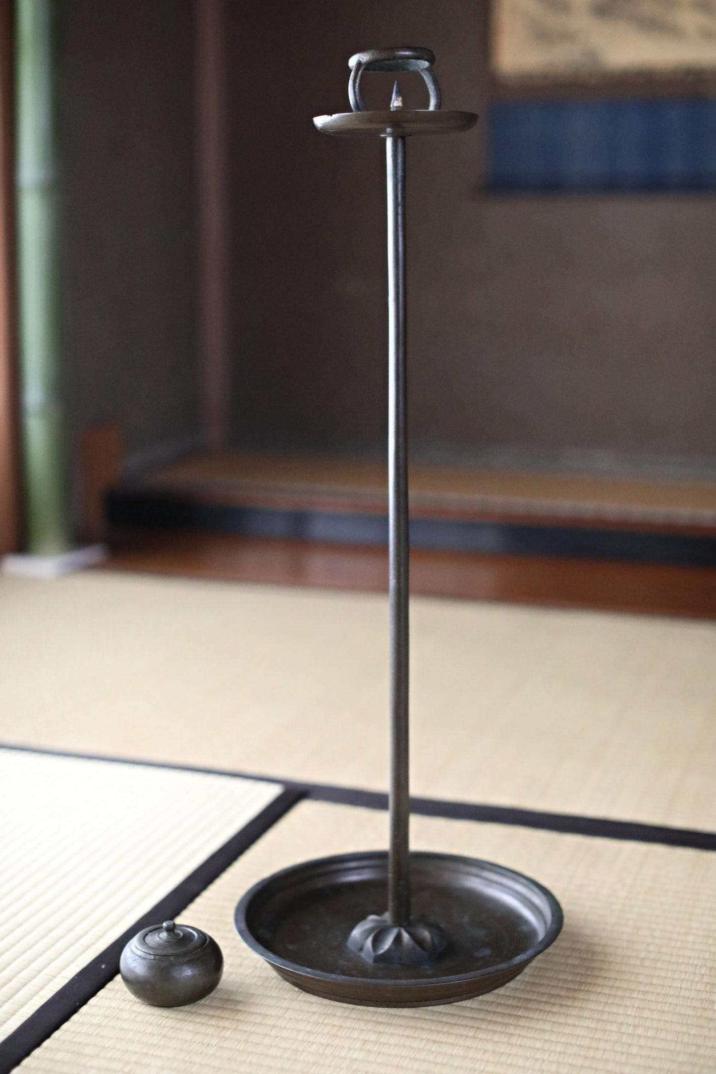 a black metal candlestick holder with a round bowl on a wooden surface.