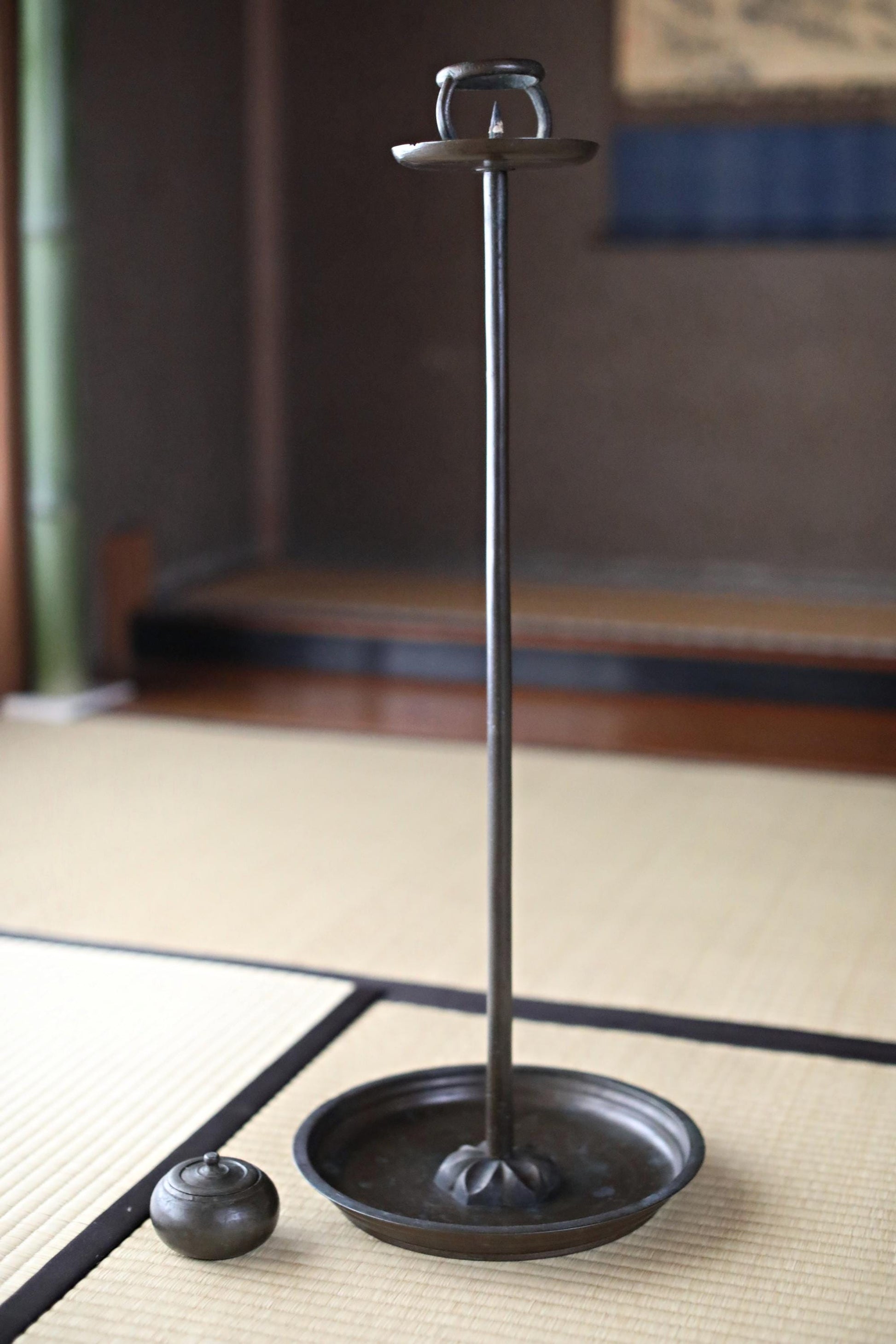 a black metal candlestick holder with a round bowl on a wooden surface.