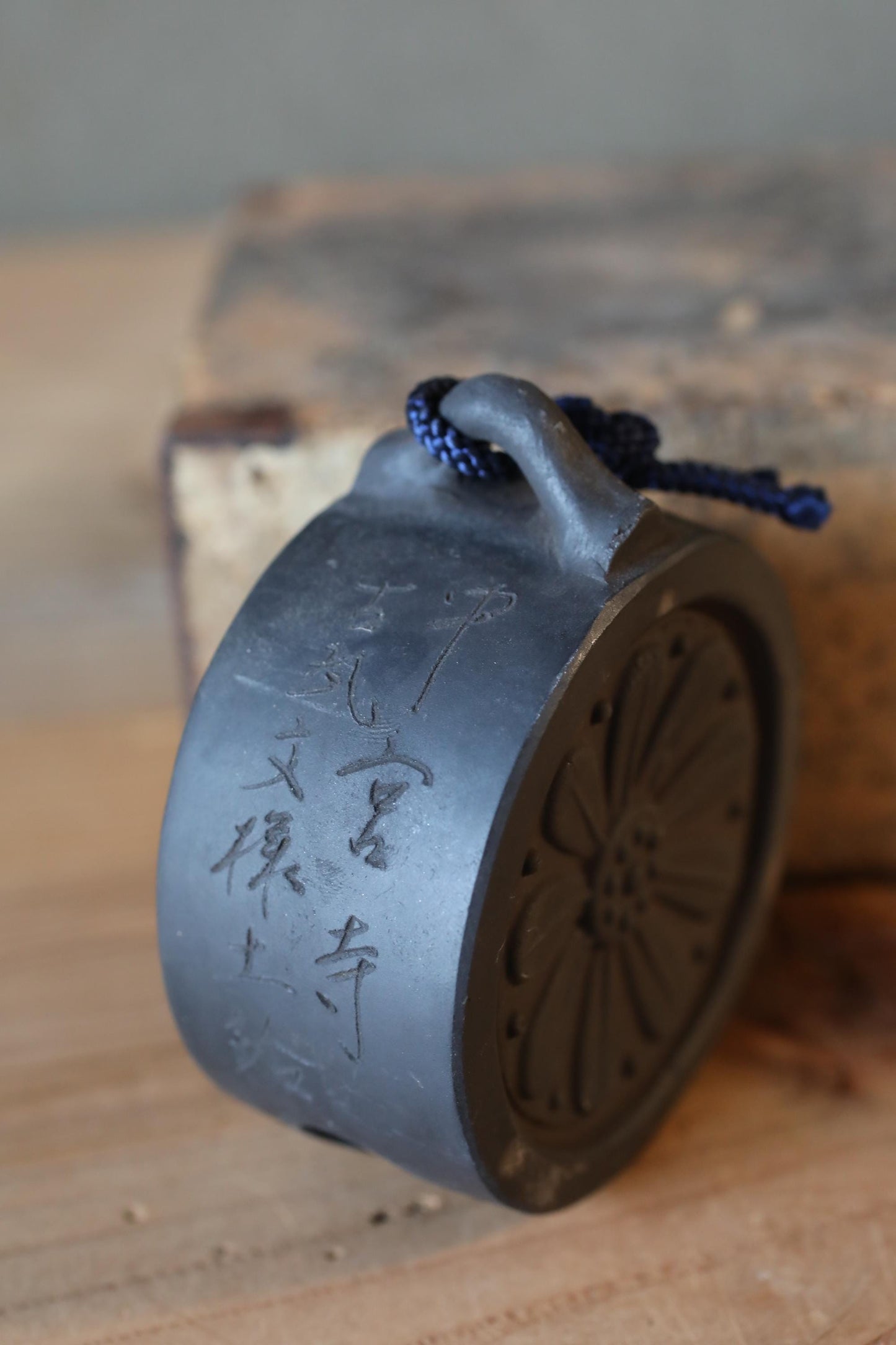 A black metal object with Chinese characters engraved on it, hanging on a wooden surface.