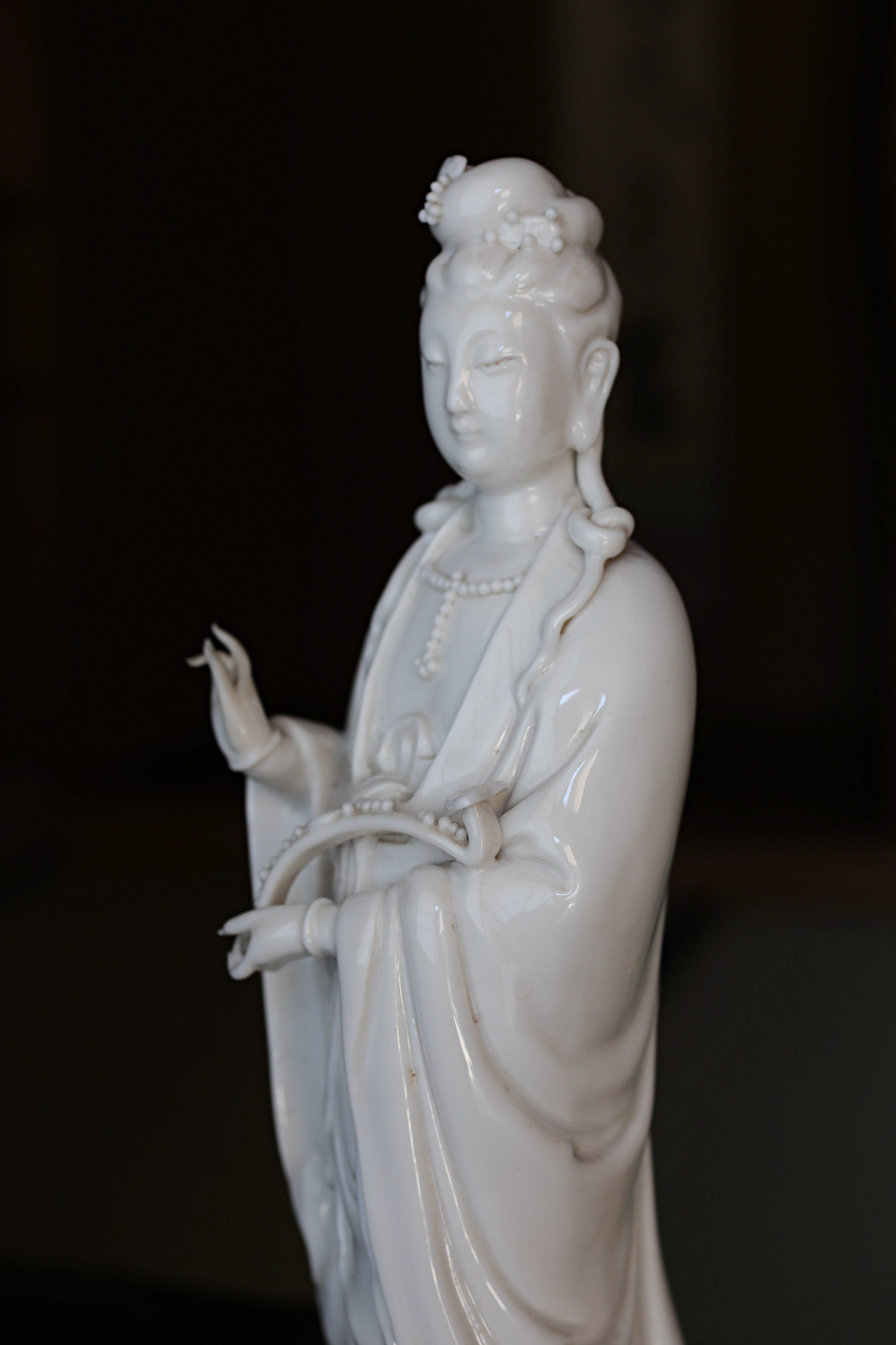 A white porcelain figurine of a female deity, possibly a goddess or deity, with an ornate headdress and holding a musical instrument.