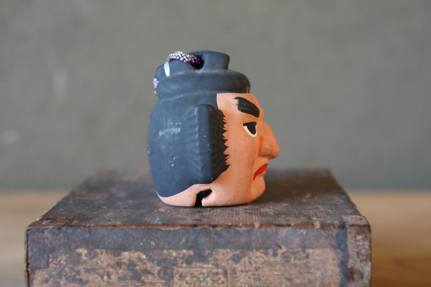 A ceramic figurine of a man's face is sitting on a wooden surface.