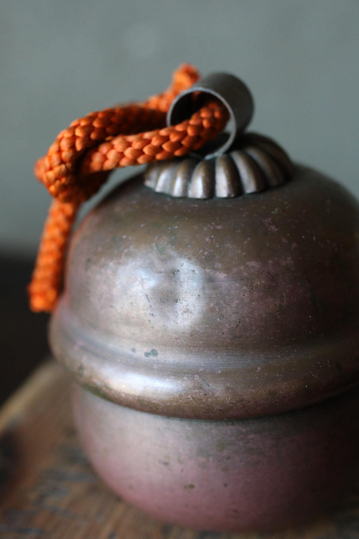 A close-up image of a metal bell with a red string hanging from it.