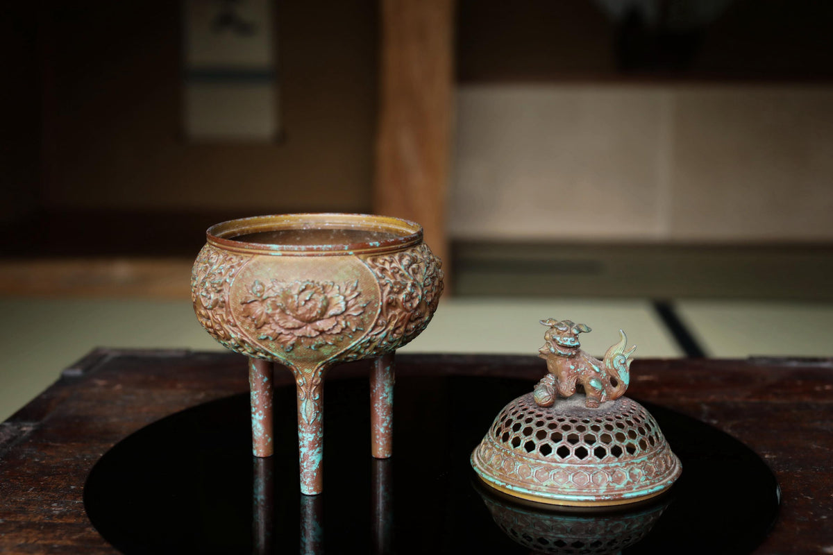 a decorative metal bowl with a lid, placed on a wooden surface.
