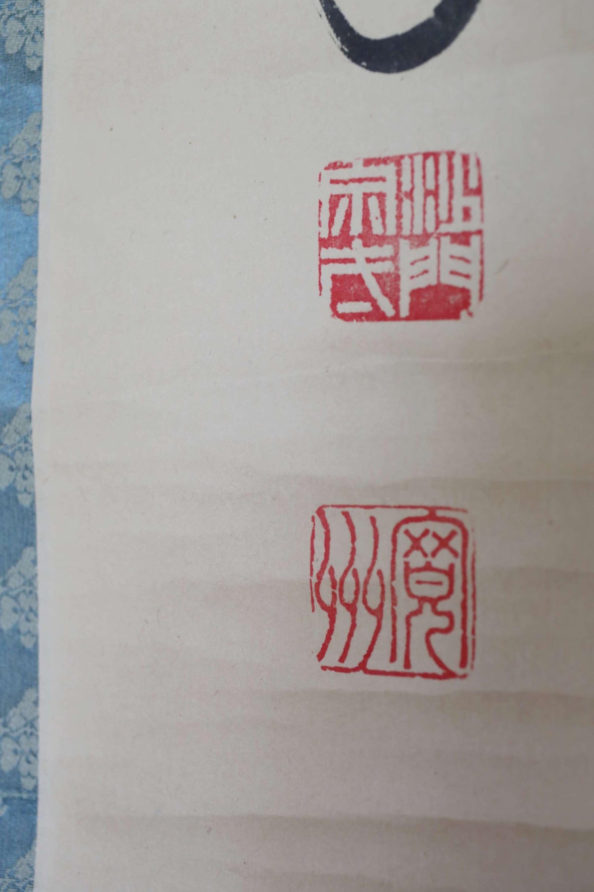 a close-up view of a white surface with two red Chinese characters and a black symbol. The characters appear to be in a traditional Chinese script, and the symbol is a simple black circle. The image does not contain any text or additional objects, and the relative positions of the characters and symbol are clearly visible.