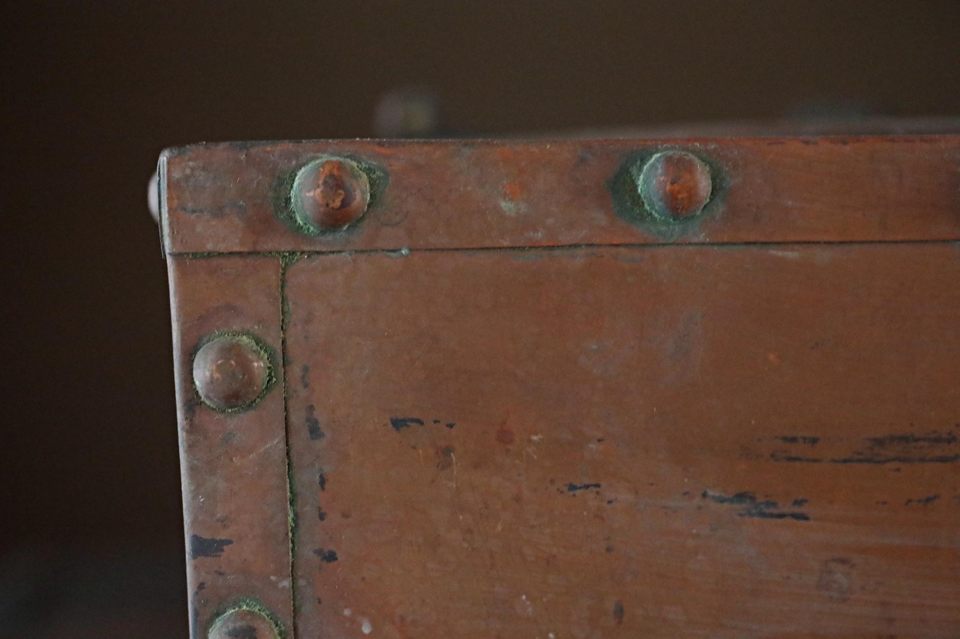 a close-up view of a rusted metal surface, possibly a piece of furniture or a metal box, with two screws visible on the surface.