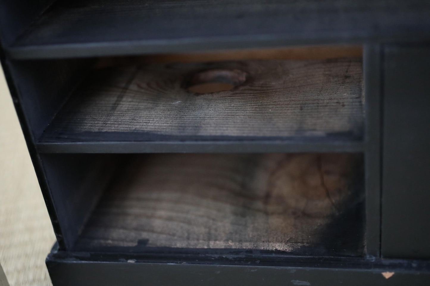 a close-up view of a wooden shelf or cabinet with a dark finish, featuring a natural wood grain texture.