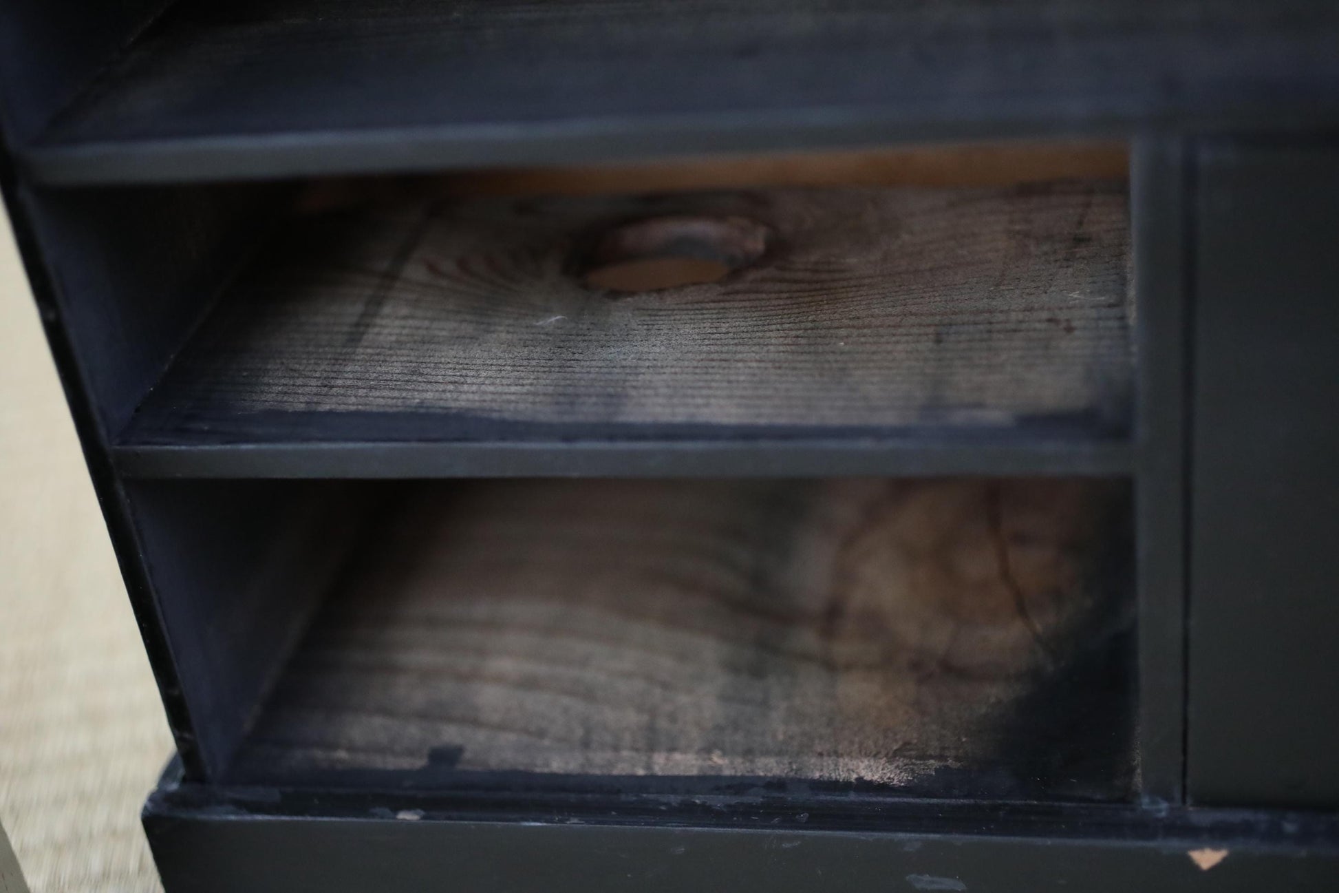 a close-up view of a wooden shelf or cabinet with a dark finish, featuring a natural wood grain texture.
