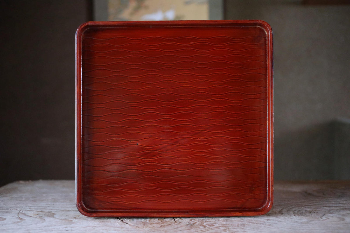 A red square tray with a wavy pattern on its surface.