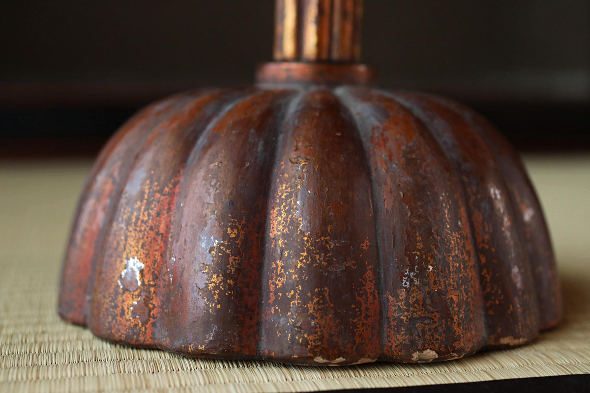 a close-up view of a rusted metal object, possibly a lampshade or a decorative piece, with a textured surface and a reddish-brown color.