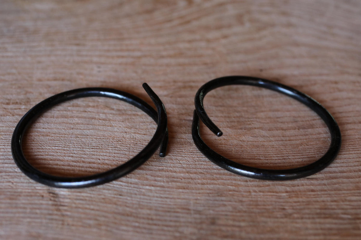 Two black metal rings lying on a wooden surface.