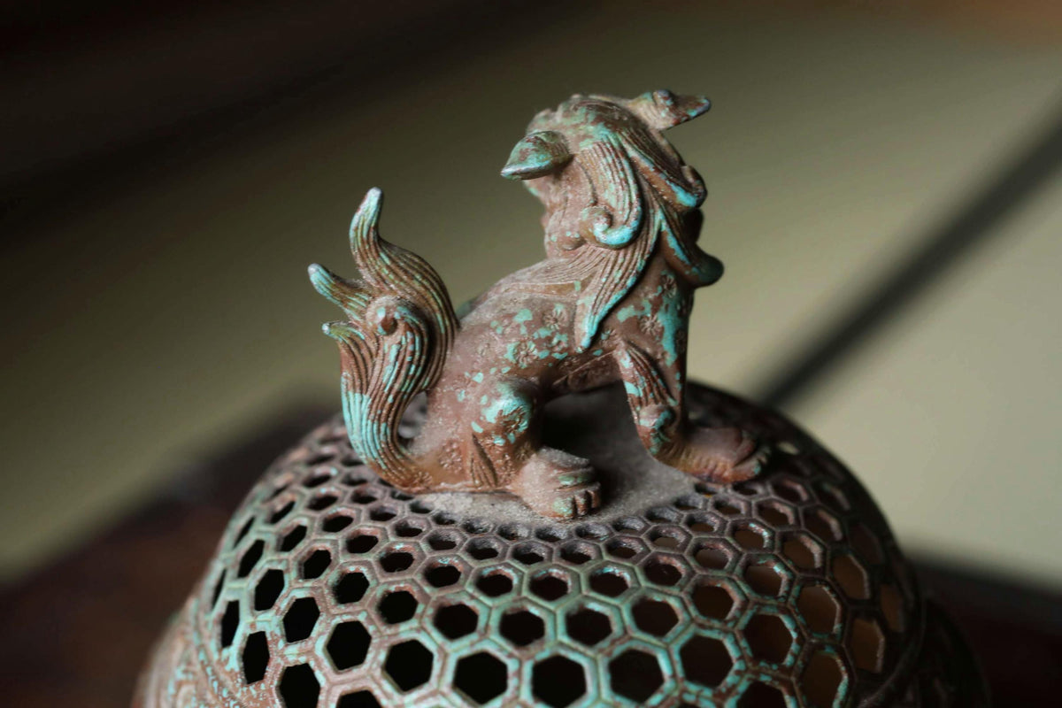 A close-up image of a bronze statue of a lion, with intricate details and a textured surface.