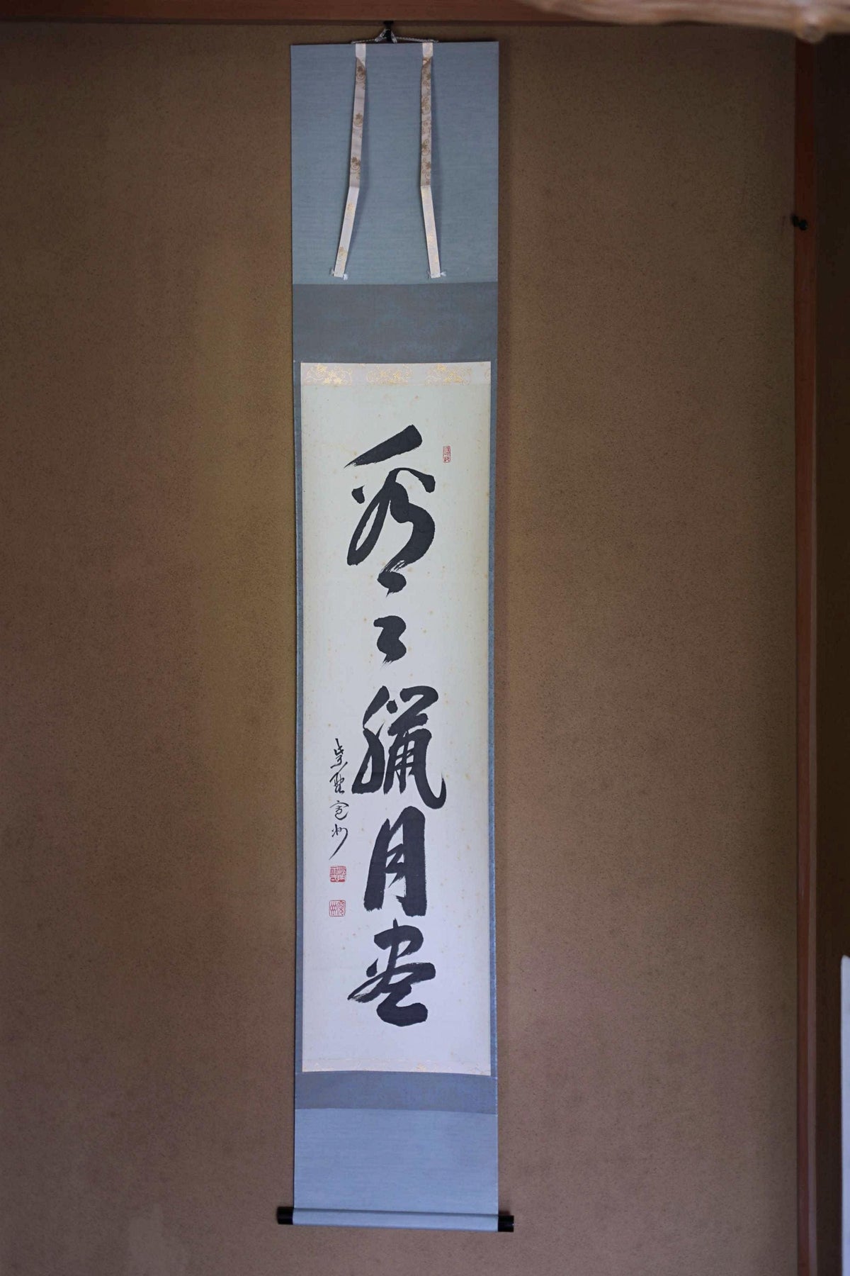 a vertical banner with Japanese text on it, hanging on a wall.