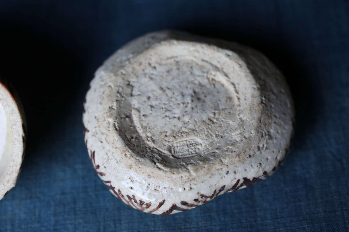 A close-up image of a white ceramic object with a textured surface, resting on a blue surface.