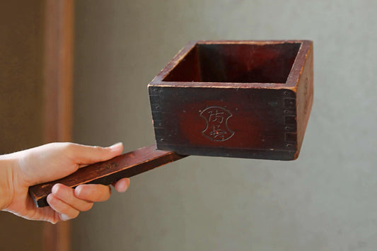 A hand is holding a wooden box with a lid, and the lid is being lifted off the box.