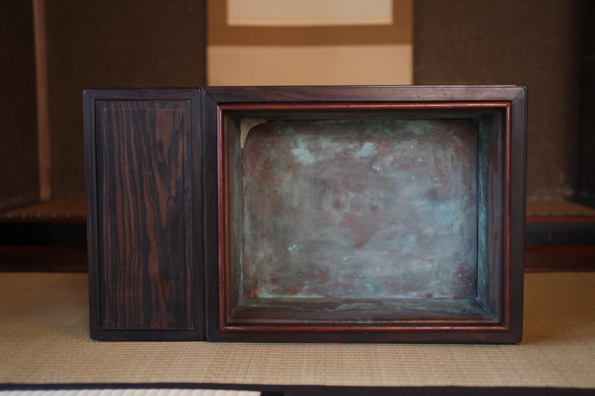 a wooden box with a metal frame, sitting on a mat.