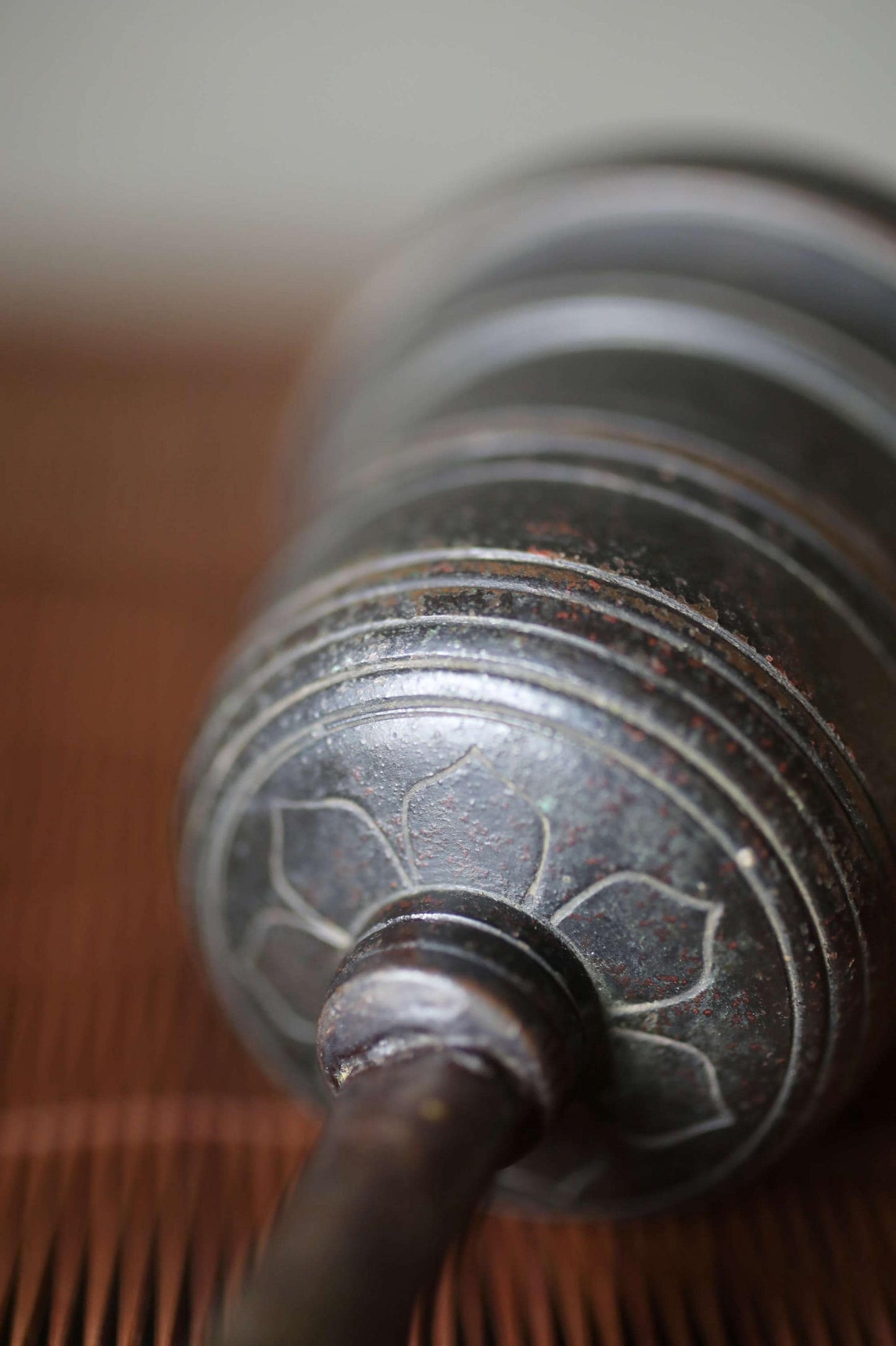 A close-up view of a metal object with a decorative pattern on its surface, resting on a wooden surface.